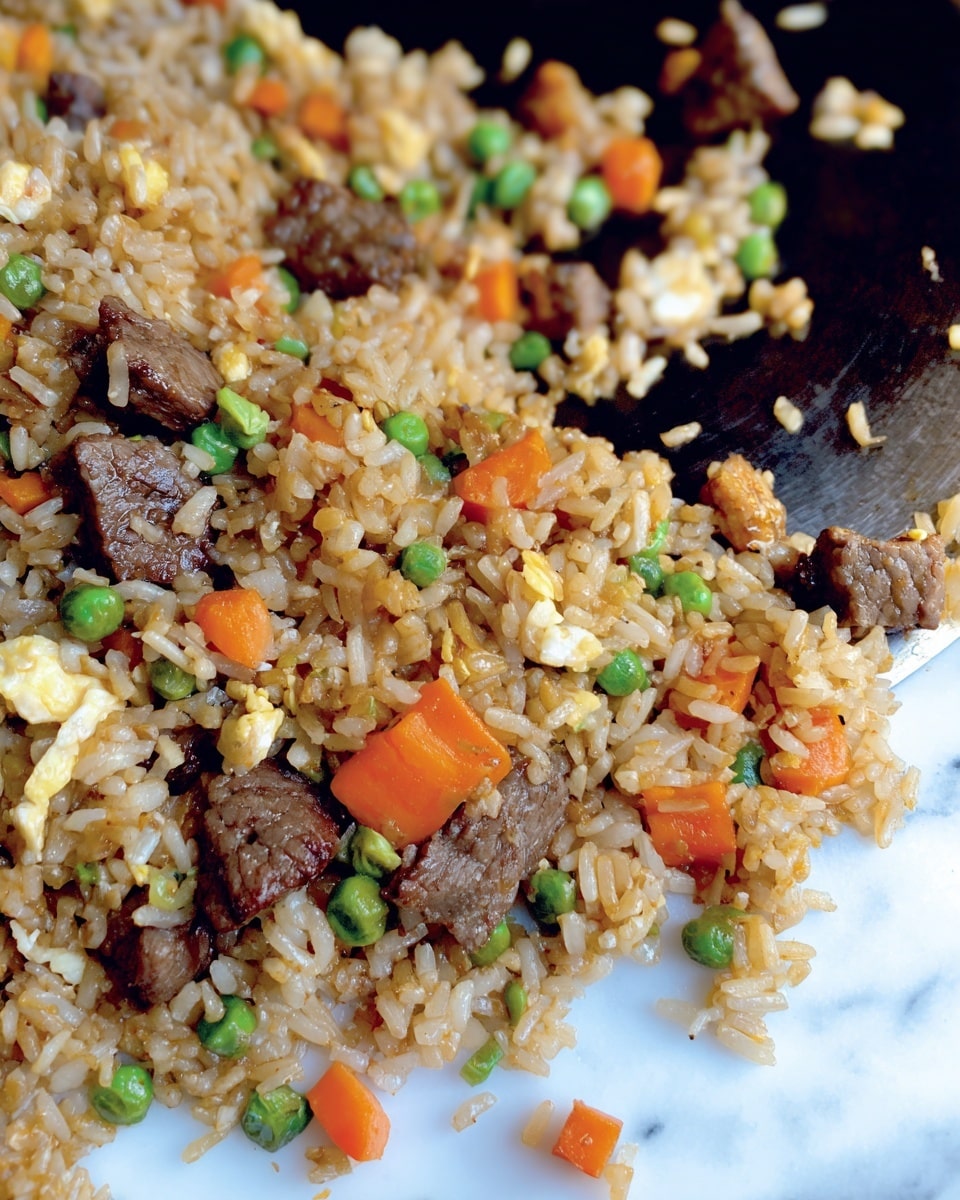A close-up view of fried rice on a large white plate with small pieces of orange carrots, green peas, and brown beef cubes mixed evenly among the light brown cooked rice. The food looks moist and shiny, scattered across the plate with some grains sticking out, showing a slightly oily texture. The background is a white marbled surface. Photo taken with an iphone --ar 4:5 --v 7