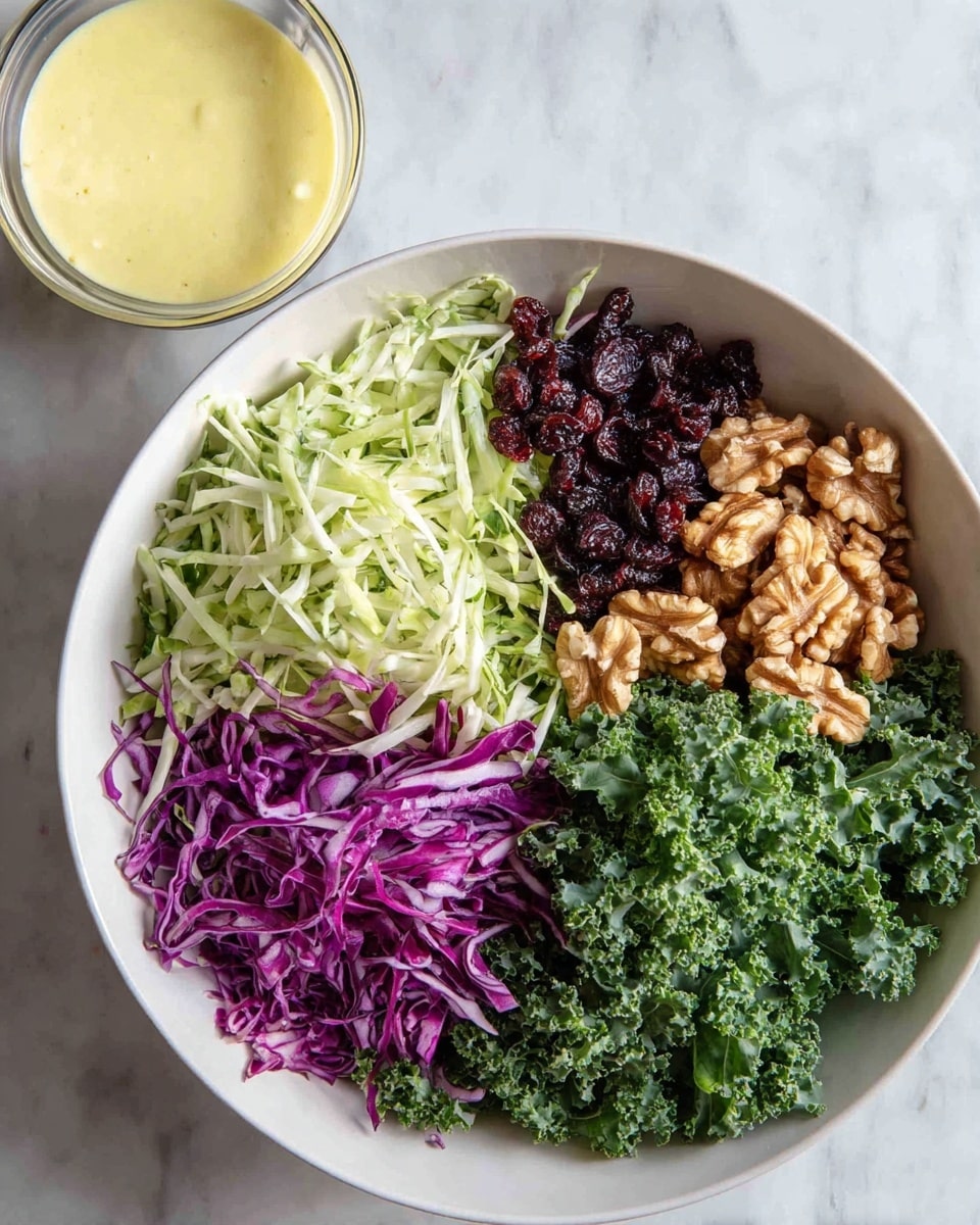 A white bowl on a white marbled surface holds a fresh salad with five layers arranged in sections: dark green curly kale on the right, light green shredded cabbage mixed with kale leaves below the kale, bright purple shredded cabbage on the bottom left, light brown walnut pieces above the purple cabbage, and dark dried cranberries at the top. On the upper left corner outside the bowl is a small glass bowl filled with creamy light yellow dressing. Photo taken with an iphone --ar 4:5 --v 7