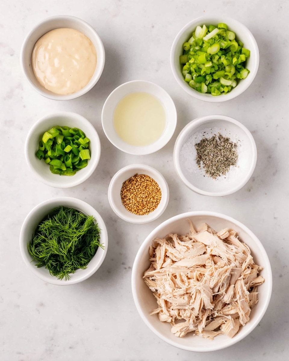 The image shows eight small white bowls arranged neatly on a white marbled surface. The largest bowl at the bottom right is filled with shredded light tan chicken meat. To its left, a medium bowl holds a smooth pale beige sauce or mayo. Above this sauce bowl is a small bowl with a clear liquid, likely lemon juice. Surrounding these are six small bowls: finely chopped bright green celery pieces at bottom left, chopped green onions mixed with parsley at bottom right, fresh green dill leaves at top left, whole grain mustard with visible seeds in the middle top bowl, and white salt and black pepper mix in the top right bowl. The colors range from pale beige and white to different bright greens and golden browns, all placed on a clean, smooth white marbled surface. photo taken with an iphone --ar 4:5 --v 7