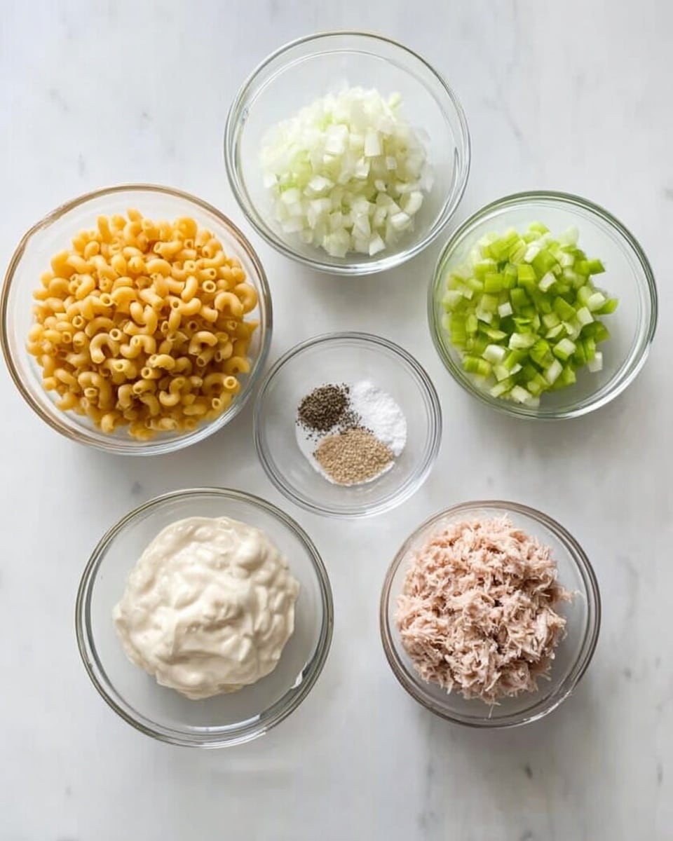 The image shows six clear glass bowls on a white marbled surface, arranged in a circle. The top left bowl has dry elbow macaroni pasta, golden yellow and curly. At the top center is a small bowl with finely chopped white onions. The top right bowl contains chopped green celery pieces. In the center is a smaller bowl with white salt topped with black pepper. At the bottom left, a bowl holds a pale creamy substance that looks like mayonnaise, smooth and thick. The bottom right bowl contains finely shredded light pink tuna. The light is soft and natural, and the photo is taken with an iphone --ar 4:5 --v 7