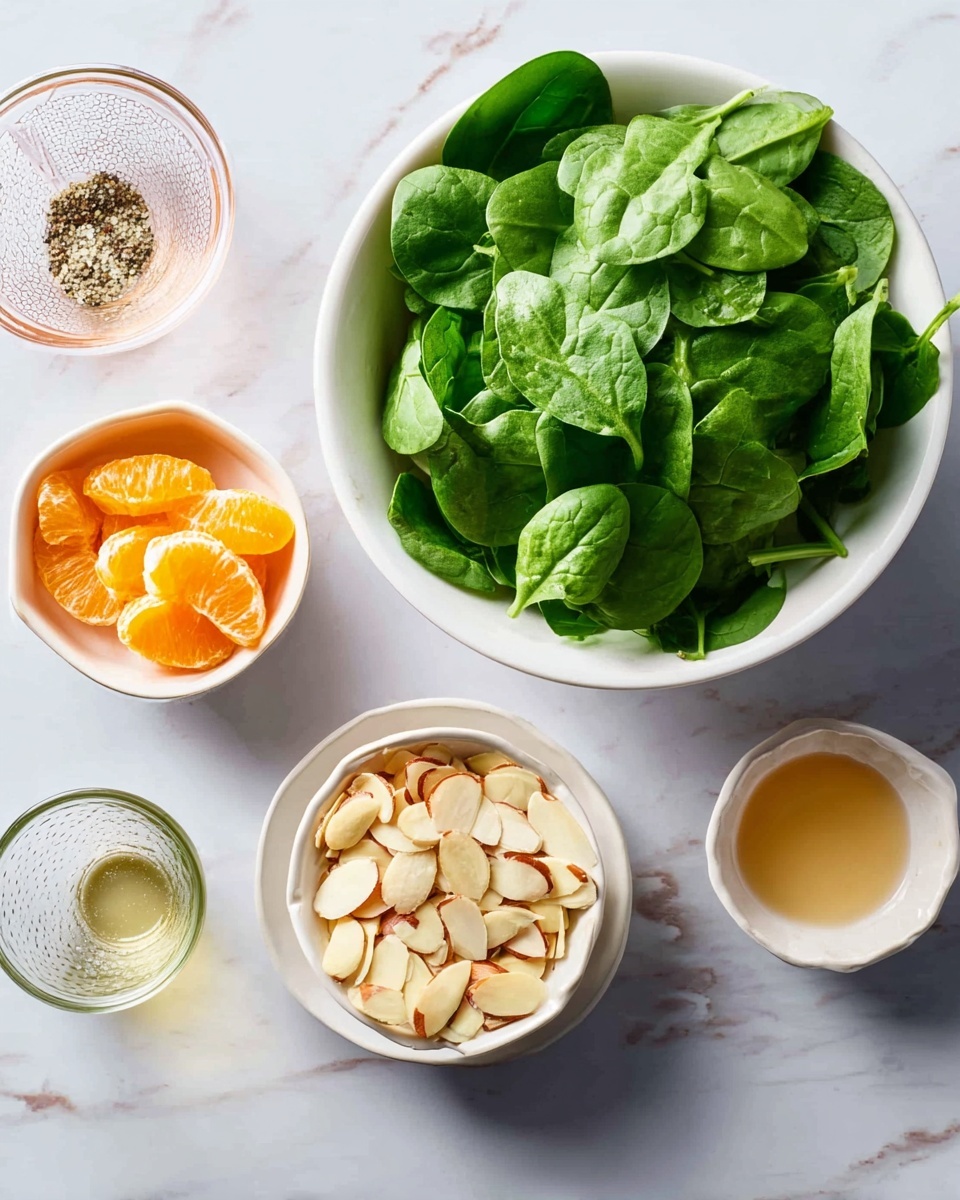 The image shows several small white bowls arranged on a white marbled surface. In the top right, there is a large white bowl filled with fresh green spinach leaves, which are bright and crisp. Below it, there is a small white bowl filled with thinly sliced almond pieces, pale cream with some brown skin edges. To the left of the almonds, another small white bowl contains peeled, bright orange mandarin segments. Above that is a small white bowl with a light brown liquid, and next to it, another small white bowl with a clear pale liquid. At the bottom left, there is a glass bowl with salt and pepper mixed inside. The scene is clean and bright, with all the bowls showing their contents clearly. Photo taken with an iphone --ar 4:5 --v 7