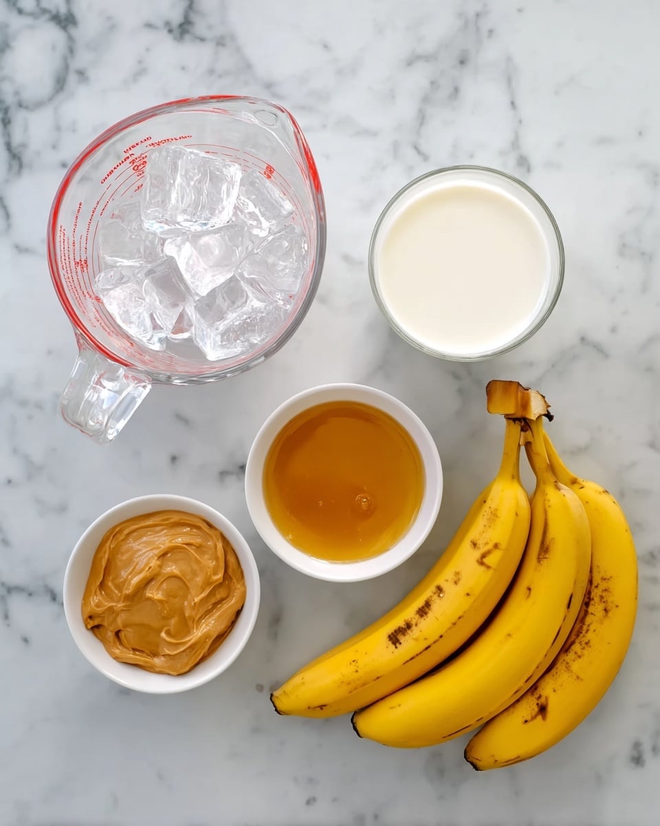 The image shows five ingredients placed on a white marbled surface. At the top left, there is a clear glass measuring cup filled with ice cubes, beside it to the right is another clear glass measuring cup filled with milk. Below them are two small white bowls, the one on the left contains golden honey, and the one on the right is filled with creamy peanut butter. To the far right, there are two whole yellow bananas with some brown spots, resting side by side. The photo taken with an iphone --ar 4:5 --v 7
