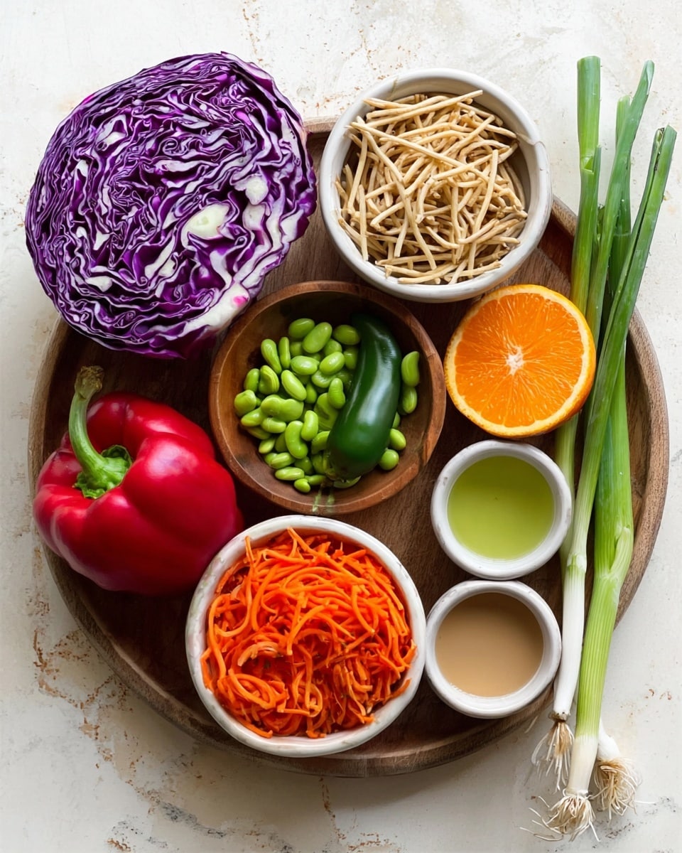 The image shows a wooden round tray holding various fresh ingredients arranged in small white bowls and directly on the tray. At the top left is a large half of purple cabbage with white veins. Below it is a white bowl filled with crunchy noodle sticks. Next to that on the tray is a green jalapeño pepper. Below the pepper is a small wooden bowl filled with green edamame beans, and next to it, a white bowl with shredded bright orange carrots. In the middle is a large orange half with visible juicy texture. On the right side of the tray are three small bowls containing light green oil, light brown creamy sauce, and a clear liquid. Beyond the bowls, there is a large red bell pepper and three green onions with long stalks, all set on a white marbled surface. photo taken with an iphone --ar 4:5 --v 7