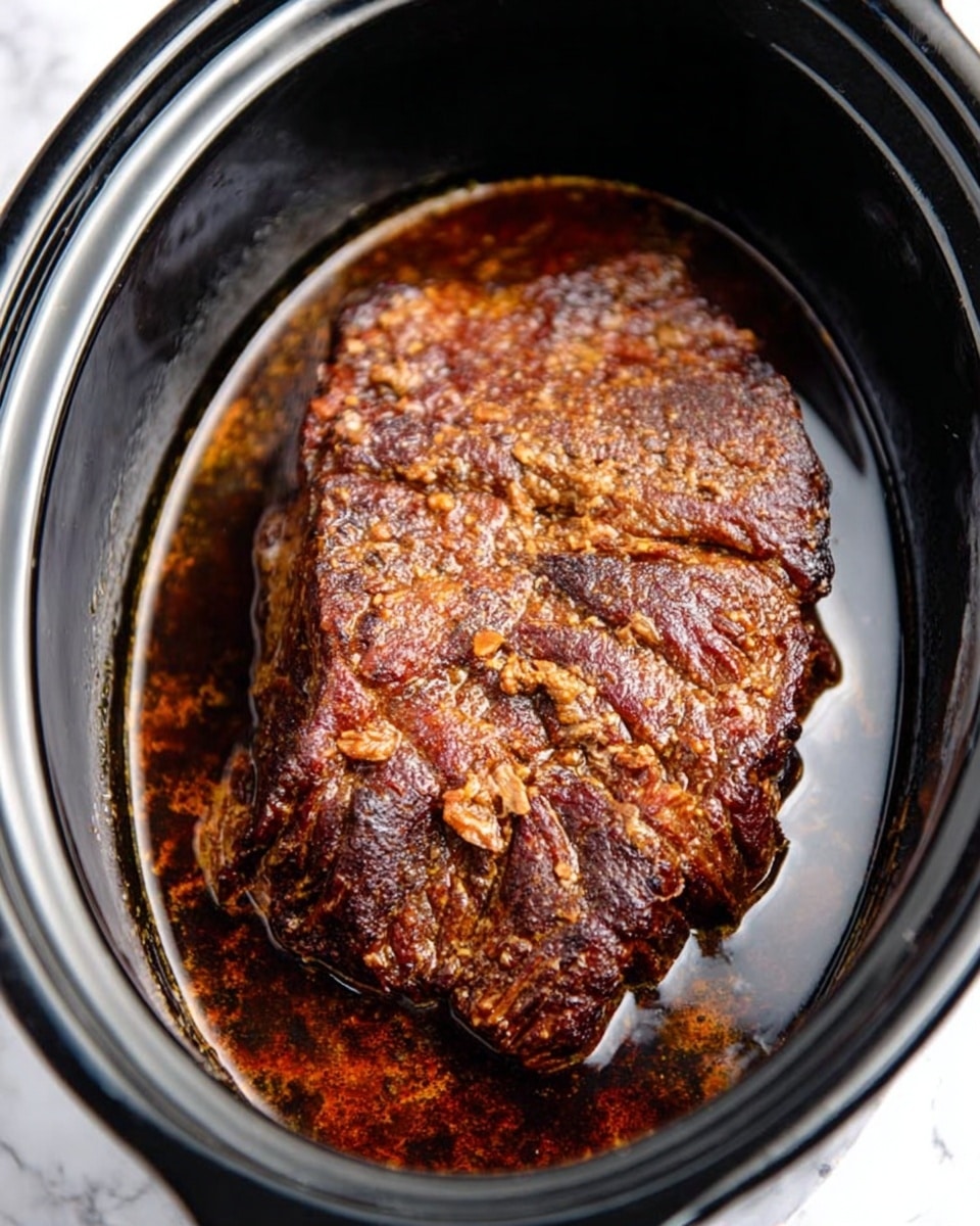 A large, dark brown piece of cooked meat with a crusty, textured surface sits in a black slow cooker filled with dark cooking juices that cover the bottom, giving a shiny, rich look to the scene. The meat has uneven, rough edges and is surrounded by the glossy liquid inside the smooth, black oval shape of the cooker. The background is a white marbled texture. photo taken with an iphone --ar 4:5 --v 7