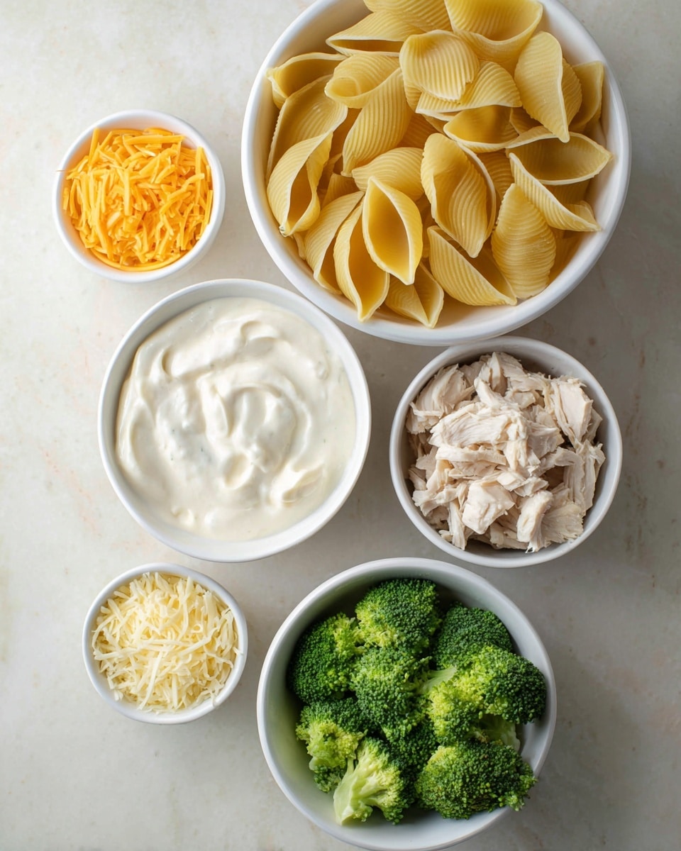 The image shows six white bowls placed on a white marbled surface, each filled with different ingredients. The largest bowl at the top holds yellow pasta shells with a smooth ridged texture, slightly overlapping each other. Below it, a bowl is filled with a thick, creamy white sauce with slight swirls on the surface. To the right, another bowl contains small pieces of cooked chicken in light beige shades. At the bottom right, there is a bowl filled with bright green broccoli florets, showing a fresh, firm texture. To the left of the broccoli, a smaller bowl holds pale yellow shredded cheese, while above it, another small bowl contains orange shredded cheese with a fine texture. photo taken with an iphone --ar 4:5 --v 7