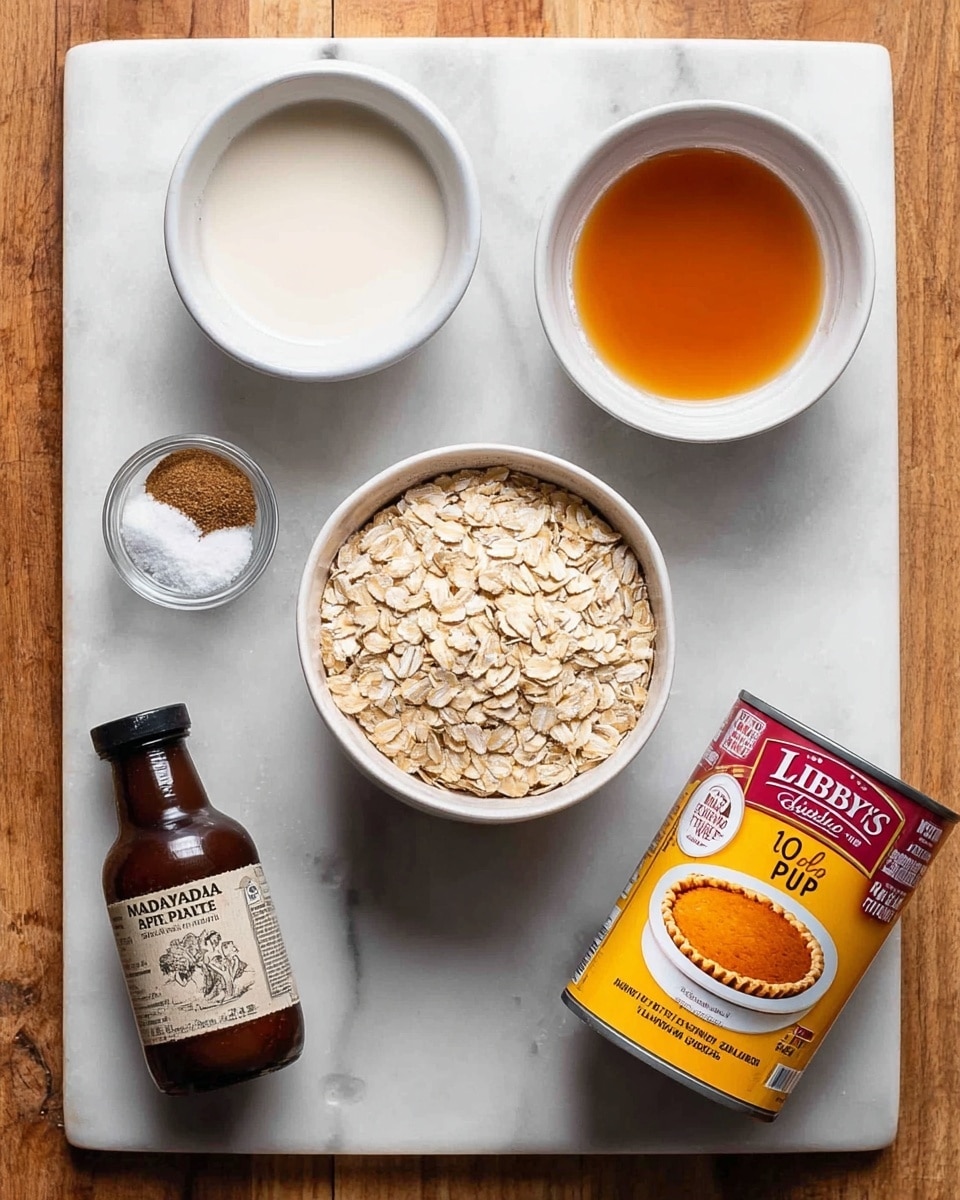 A top-down view of ingredients arranged on a white marbled surface, including a white bowl filled with light beige rolled oats in the center, a white bowl with amber-colored liquid to the top right, a small white bowl with three piles of white and brown spices to the top left, a small dark brown bottle labeled