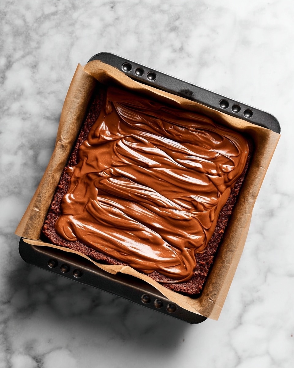 The image shows a square black baking pan lined with parchment paper. Inside the pan is one thick layer of smooth, rich, chocolate batter evenly spread with swirled textures on the surface, creating a glossy finish. The pan is placed on a white marbled textured surface. photo taken with an iphone --ar 4:5 --v 7